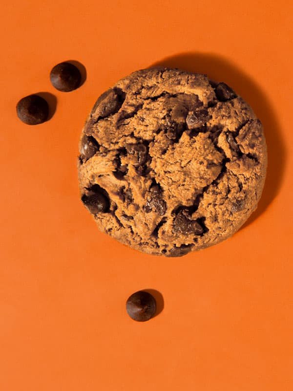 Galleta sobre fondo naranja con chispas de chocolate alrededor